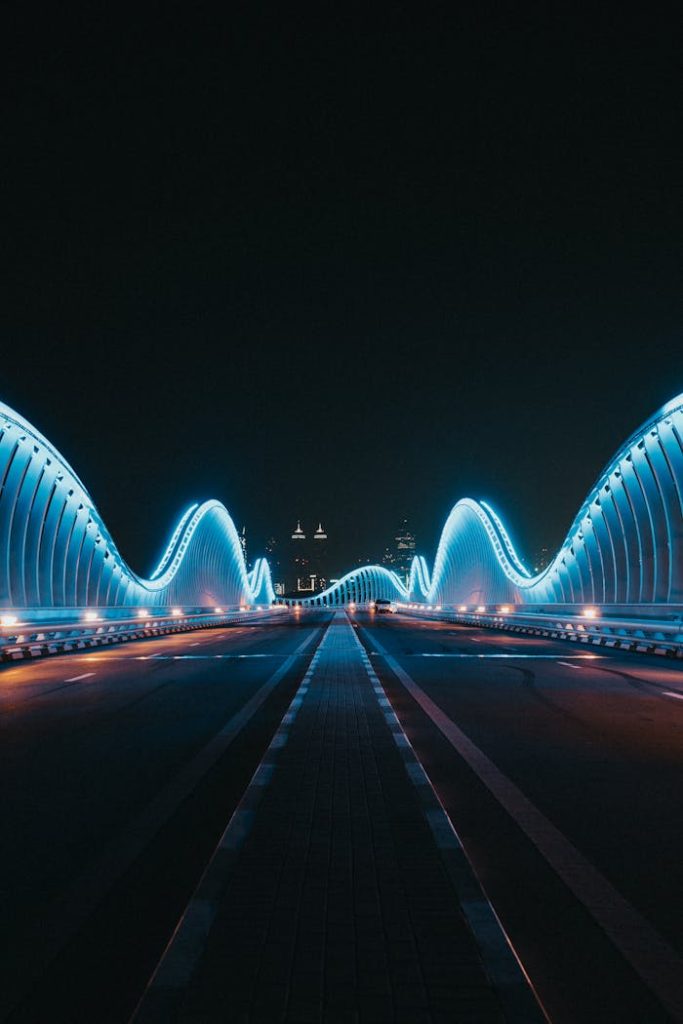 A stunning view of the Meydan Bridge in Dubai, lit up with blue lights against the night sky.